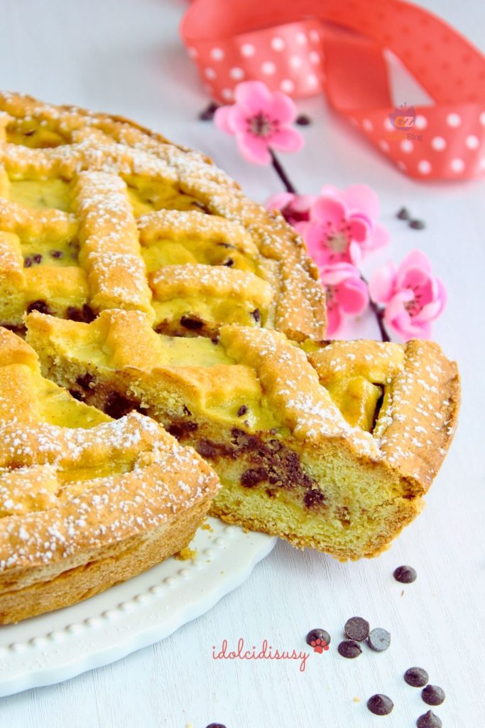 cremige Ricotta-Crostata mit Schokostückchen, angeschnittenes Stück und Puderzucker