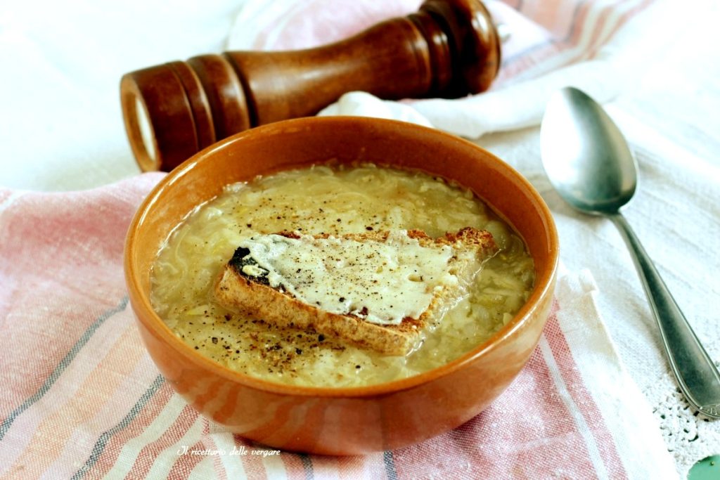 Überbackene Borettanen-Zwiebelsuppe mit Käse-Crostini und schwarzem Pfeffer in einer Terrakottaschale.