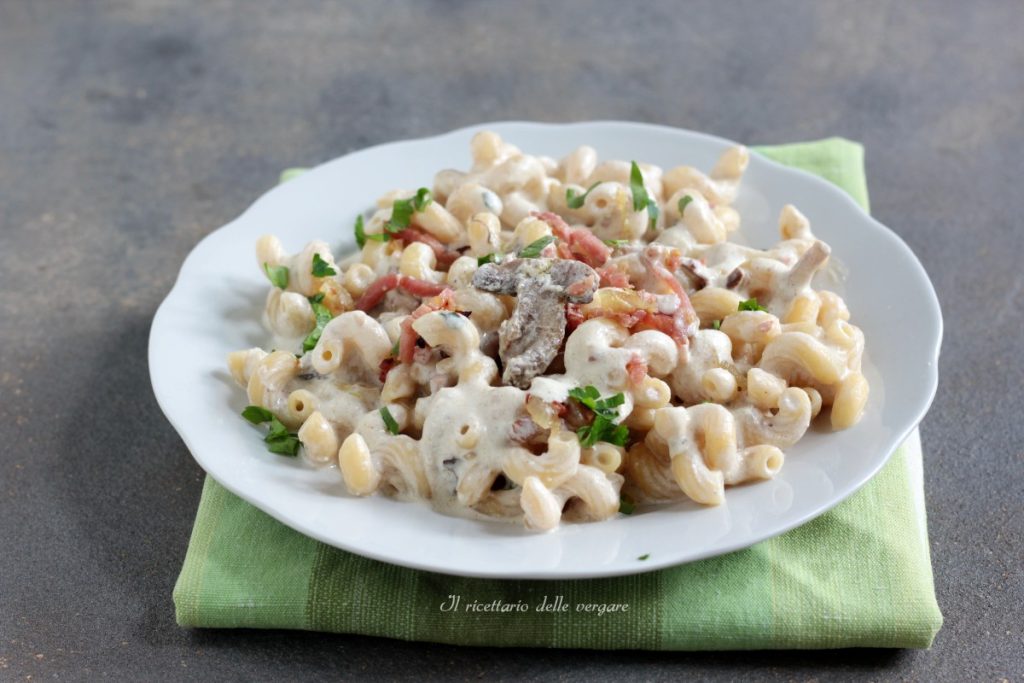 Teller mit Boscaiola-Pasta: Cellentani, knuspriger Speck und Pilzcreme auf einem grünen Servietten.