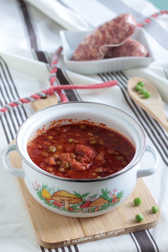 Dichte rote Soße mit Stücken von Wurst und frischen Erbsen, serviert in einer weißen Keramikschale.