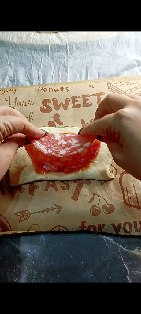 Nous remplissons avec de la sauce tomate, du salami et de la mozzarella