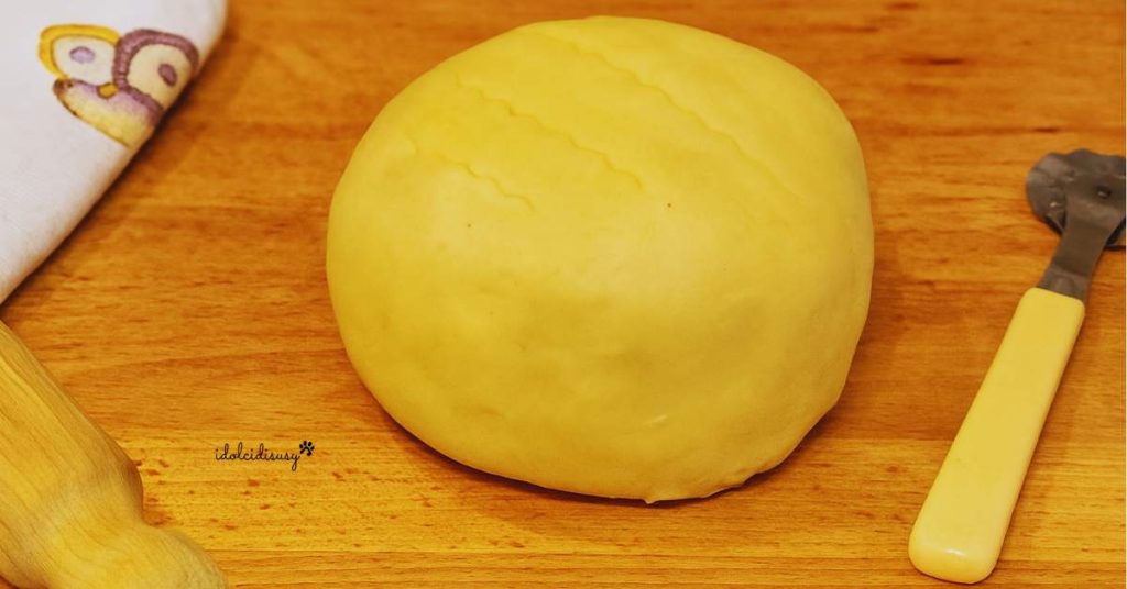 Bloc de pâte brisée fait maison sur une surface en bois avec un rouleau à pâtisserie