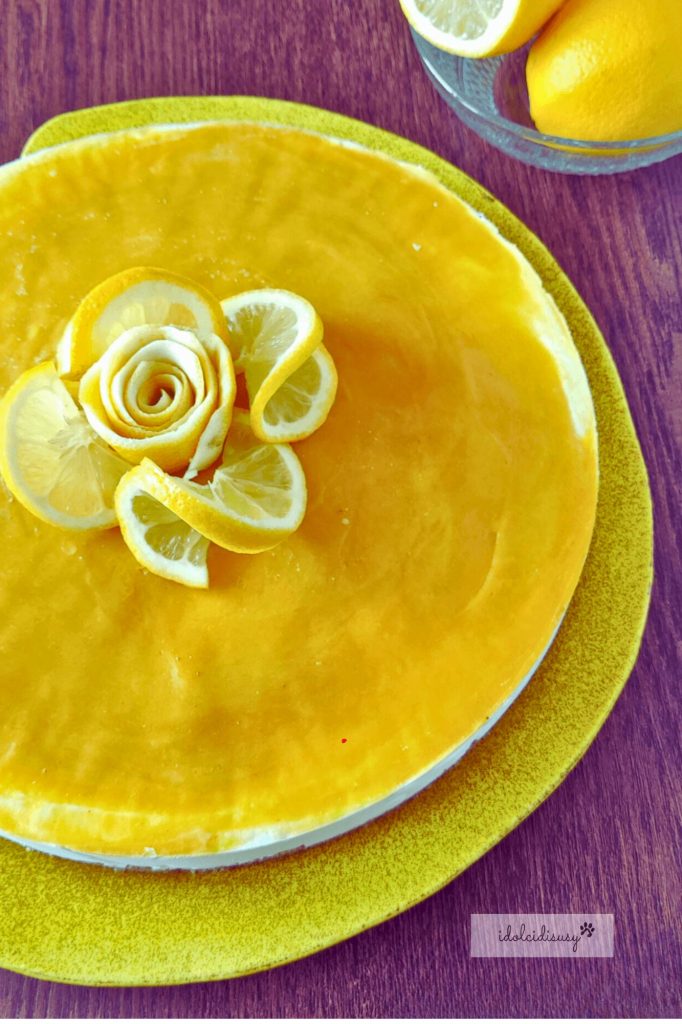 détail de la cheesecake au citron avec lemon curd brillant et rose de citron au centre, sur une assiette jaune