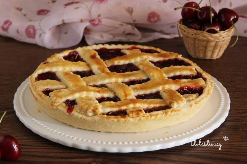 Tarte avec pâte brisée et garniture de cerises fraîches, décorée d’un tressage doré et servie sur une assiette blanche – idolcidisusy