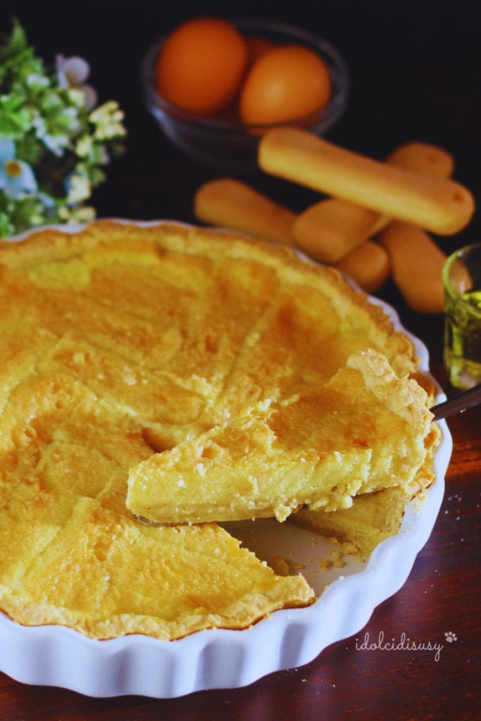 Tarte de Benevent avec une part soulevée, biscuits à la cuillère disposés en épi et crème douce au lait et liqueur Strega
