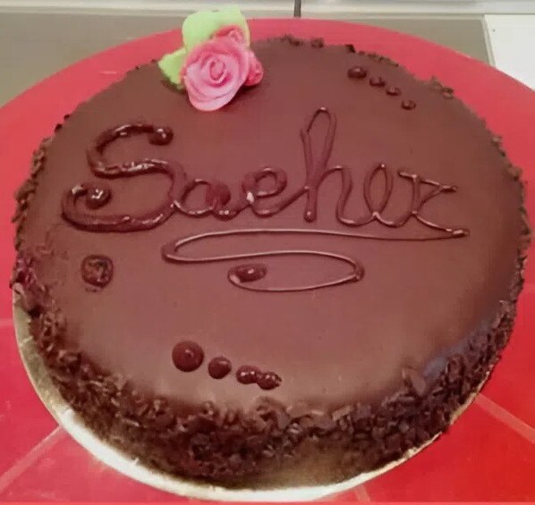 Sachertorte de l'examen avec glaçage brillant et rose en pâte à sucre