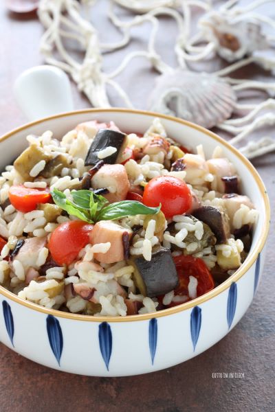 ajoutez une feuille de basilic et servez la salade de riz avec poulpe et aubergines