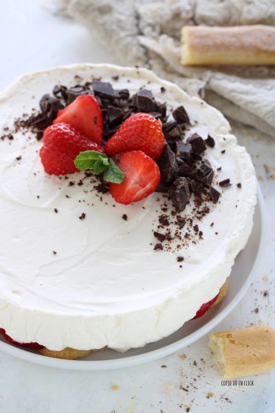 décore le gâteau avec du chocolat noir haché, des fraises et quelques feuilles de menthe