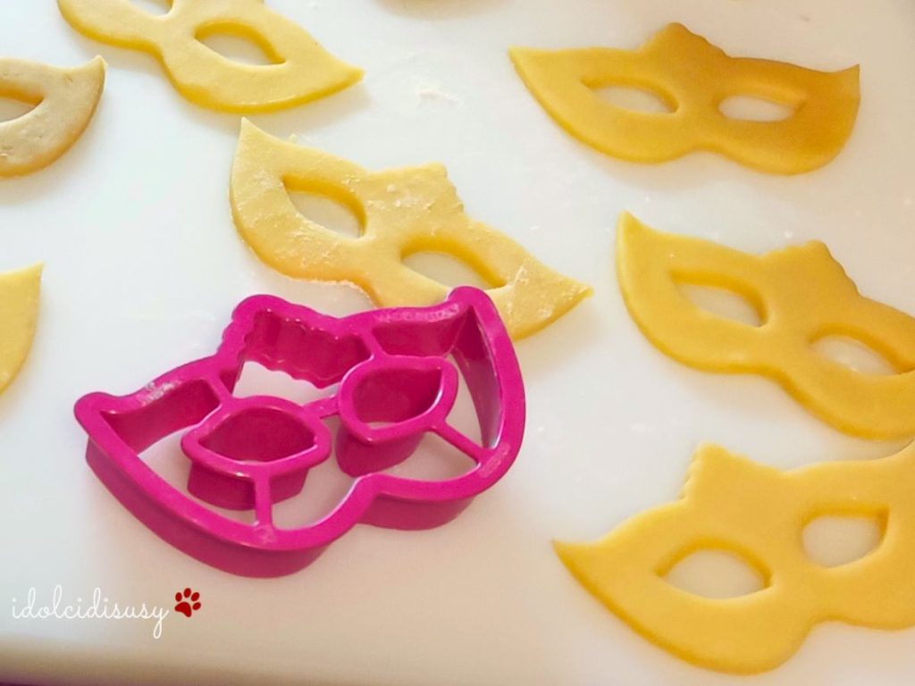 Petits masques de Carnaval en pâte sablée fraîchement découpés avec un emporte-pièce, prêts à être cuits