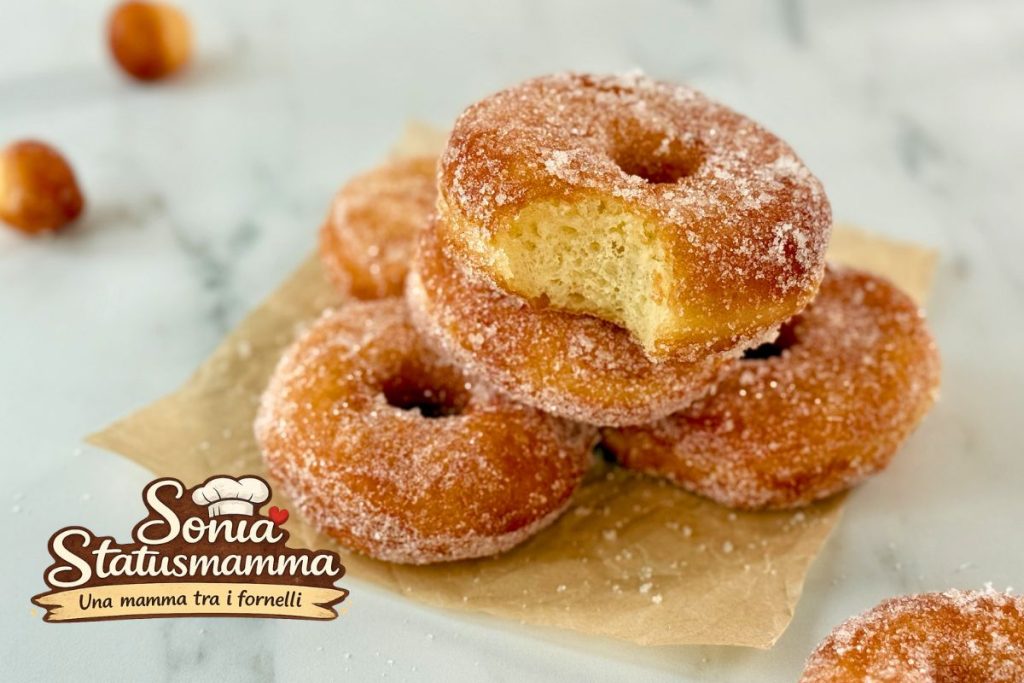 Beignets de Carnaval disposés sur un plan de marbre avec du papier sulfurisé en dessous