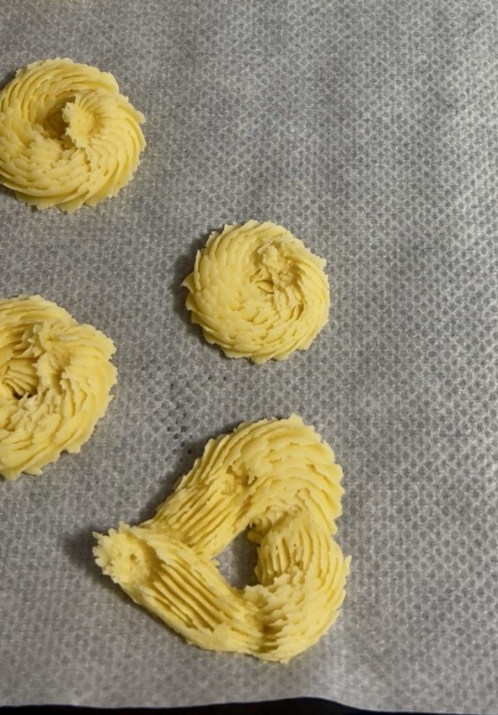 Biscuits de pâte sablée dressée crus sur plaque, certains classiques et d'autres en forme de cœur