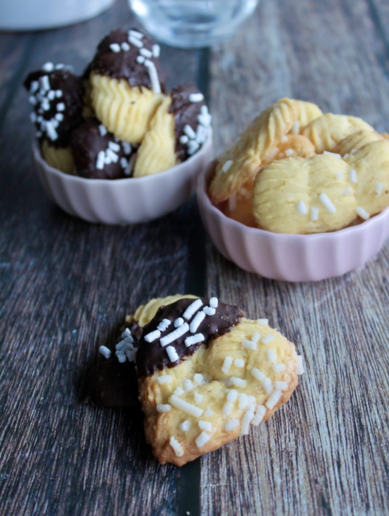 Biscuits de pâte sablée dressée en forme de cœur avec chocolat et sucres sur table en bois