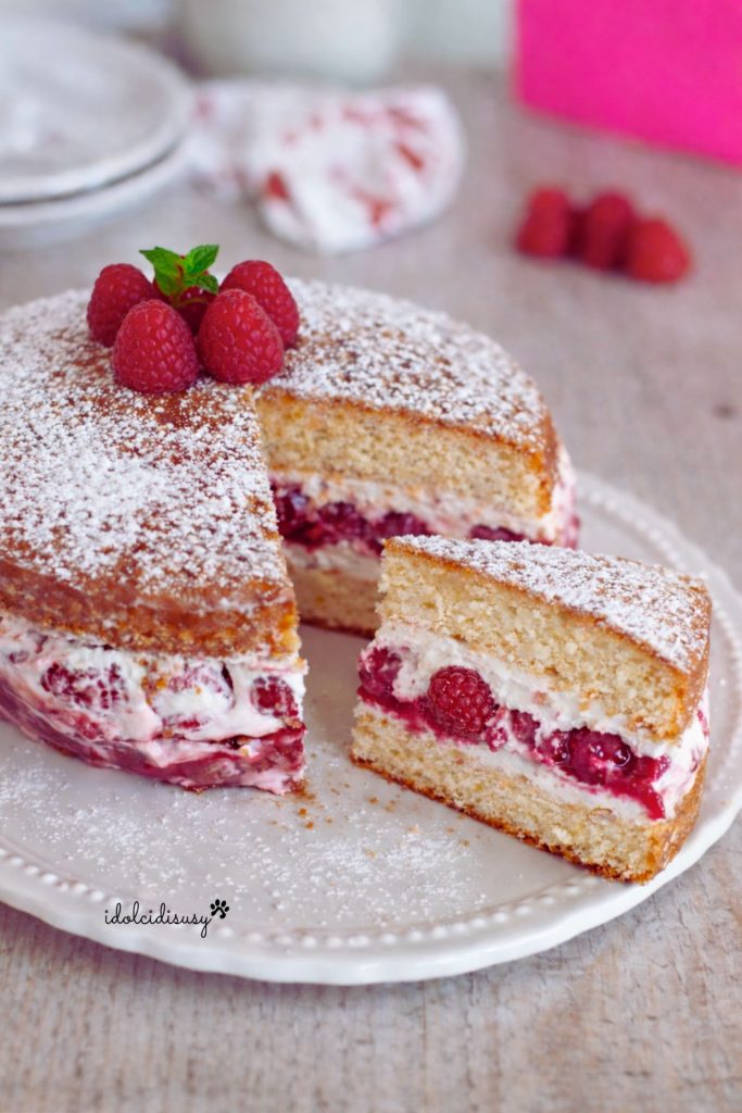 sponge cake à la crème et aux framboises avec une part coupée et la garniture visible