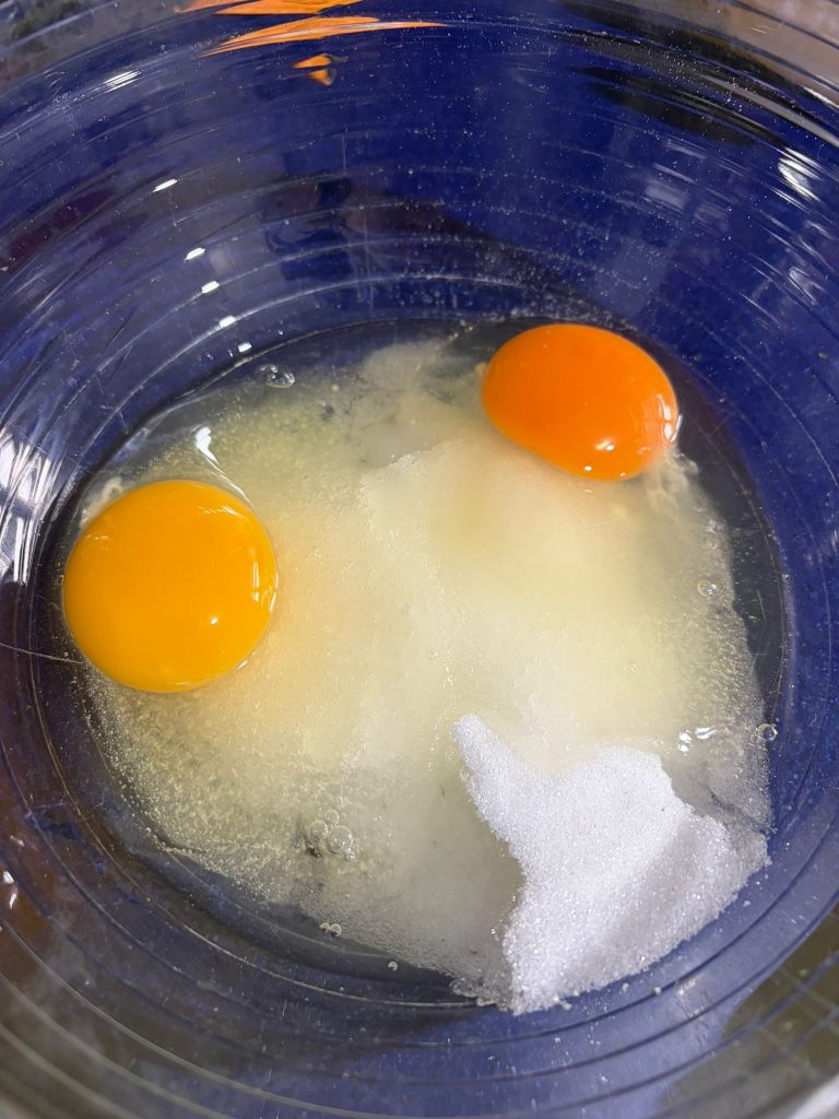 œufs et sucre dans le bol pour préparer le ciambellone à la ricotta et à l'orange