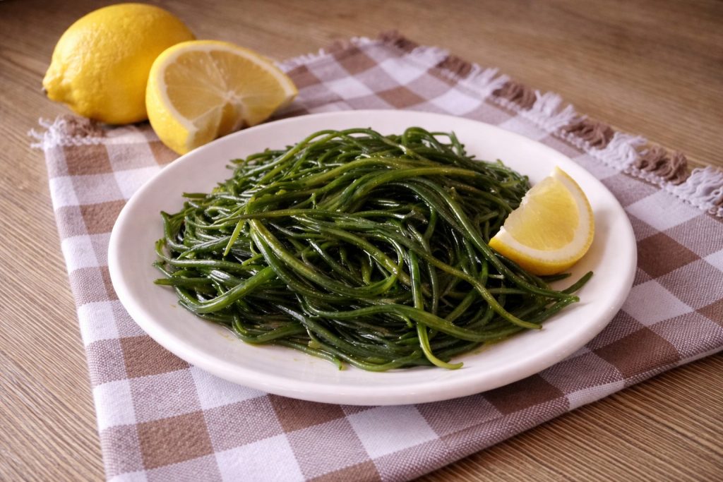 Agretti blanchis assaisonnés d'huile et de citron servis dans une assiette sur une nappe à carreaux