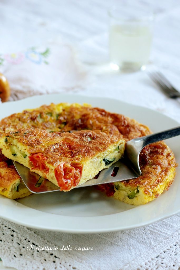 Tranche de frittata aux courgettes et tomates cerises soulevée avec une spatule en acier