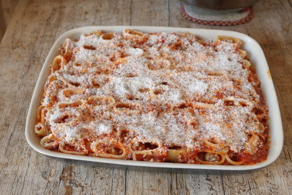 plat de paccheri avec ragù et parmesan râpé avant d'être enfournés
