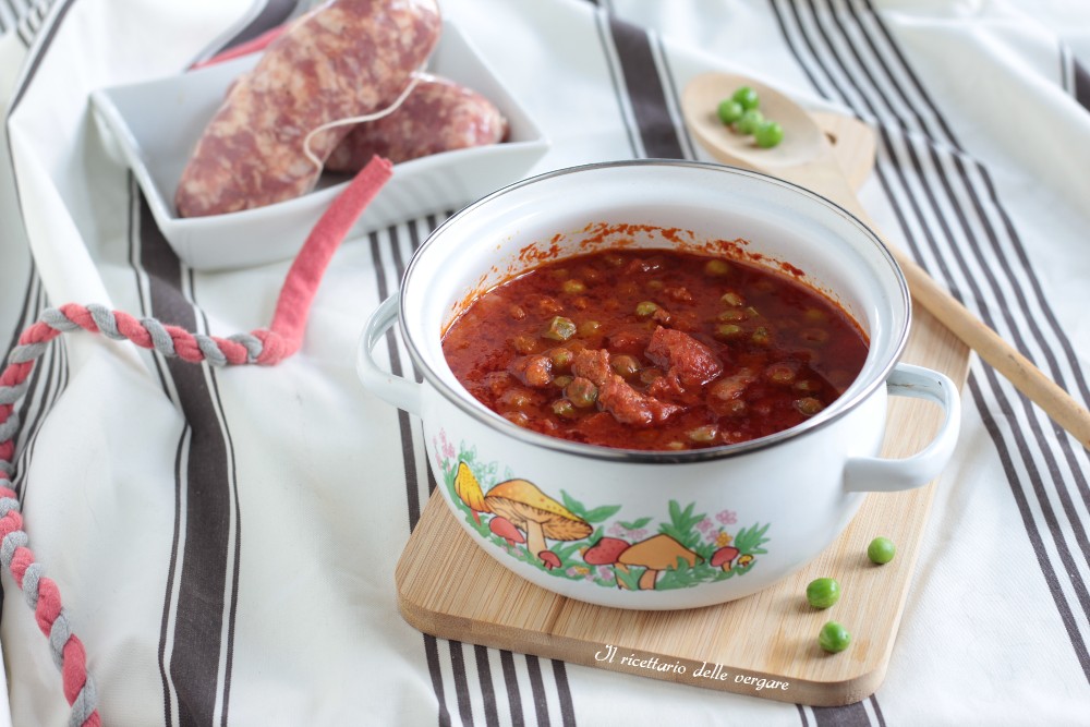 Gros plan d'un bol en céramique rempli d'une sauce rouge épaisse avec des morceaux de saucisse et des petits pois.