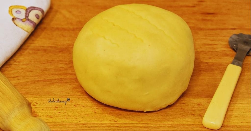 Bloque de masa quebrada casera sobre una superficie de madera con rodillo