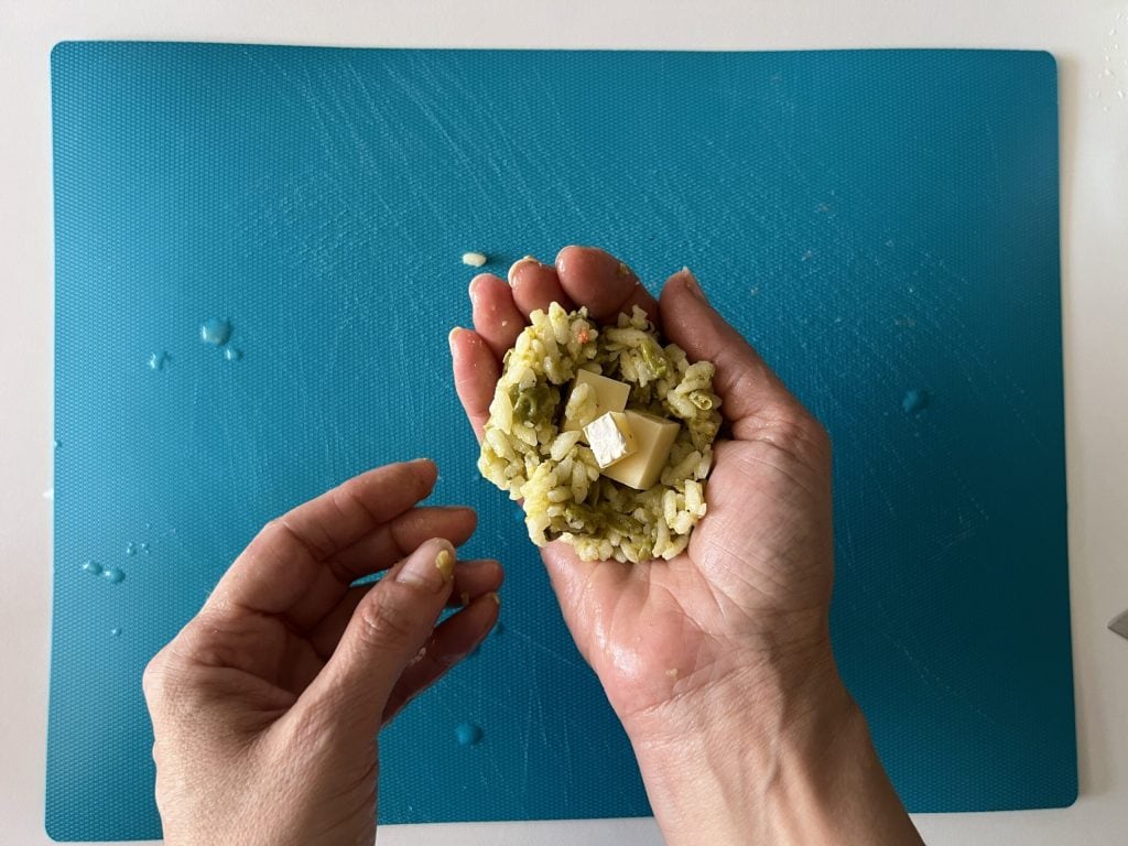 rellenar el arroz en las manos con trozos de queso
