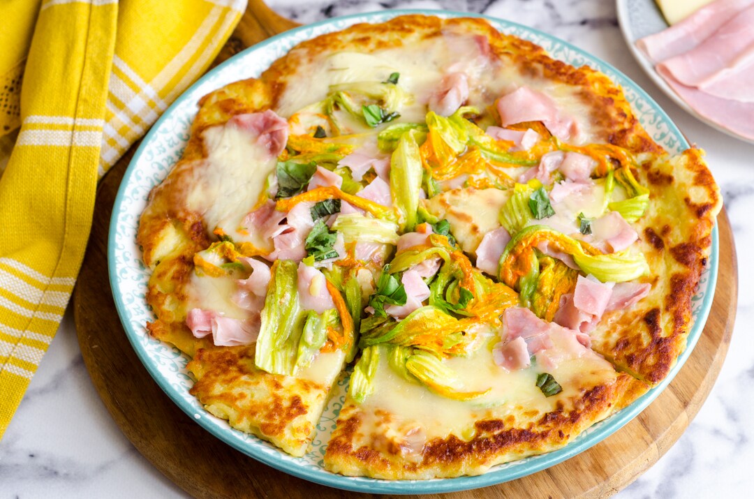 Pizza de patatas en sartén con flores de calabacín y jamón