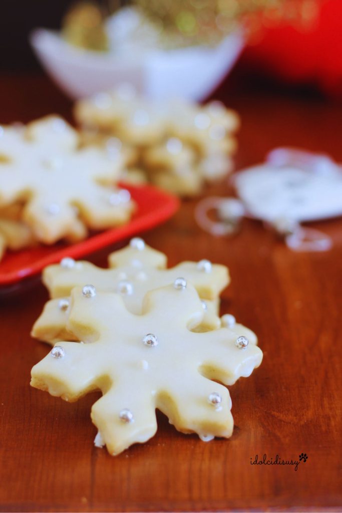 Detalle de las galletas en forma de copo de nieve con glaseado brillante y confites plateados, perfectas para regalar en Navidad