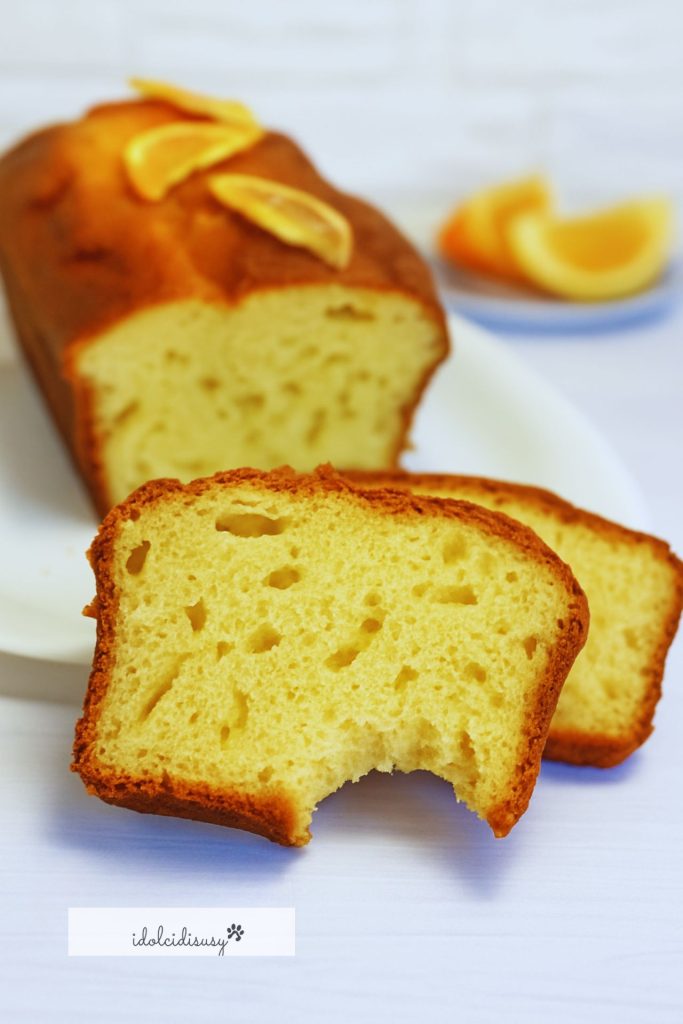 plumcake esponjoso a la naranja con una rebanada mordida, interior suave y aromático a cítricos
