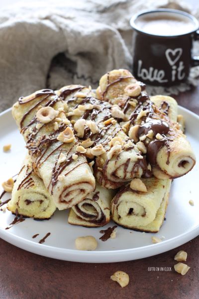coloca los rollitos de tostadas francesas en un plato y decora con crema y avellanas
