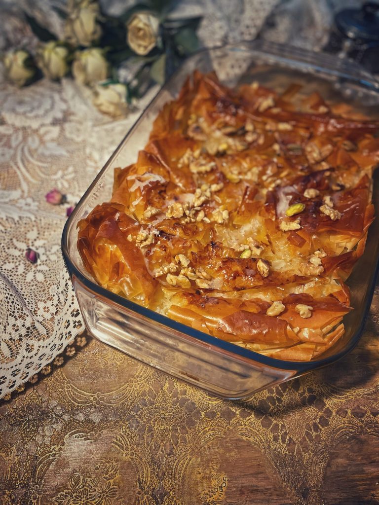 Muakacha Crinkle Cake con pistachos triturados y jarabe de rosas en un plato de servir