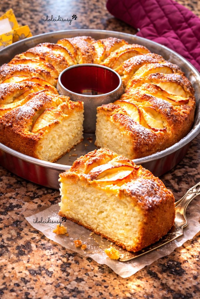 bizcocho de manzana esponjoso hecho en casa con una porción cortada, tierno y dorado con manzanas en la superficie, cocinado en molde de rosca