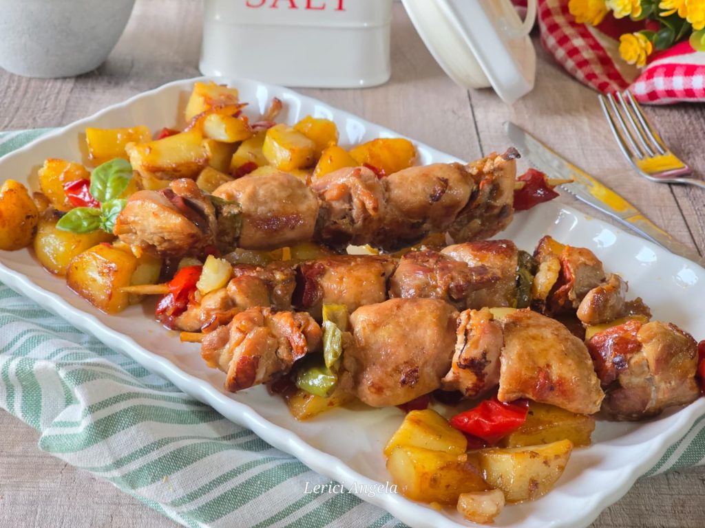 Brochetas de carne variada en sartén con patatas y pimientos