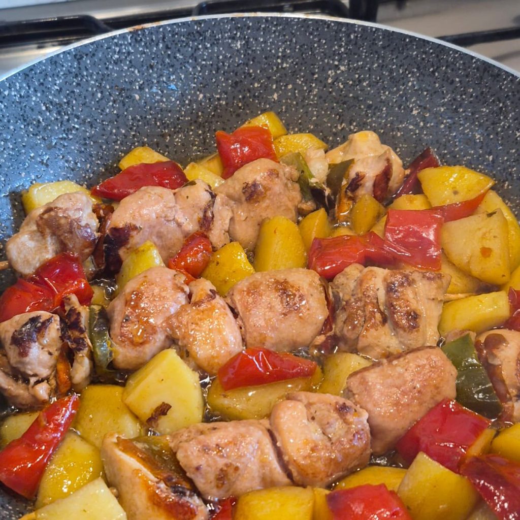 Brochetas de carne variada en sartén con patatas y pimientos