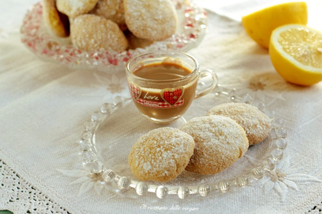 Galletitas doradas al limón hechas solo con yemas colocadas sobre una superficie con rodajas de limón fresco.