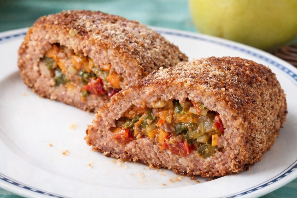 Dos lonchas de pastel de carne cocido con relleno de verduras en un plato blanco