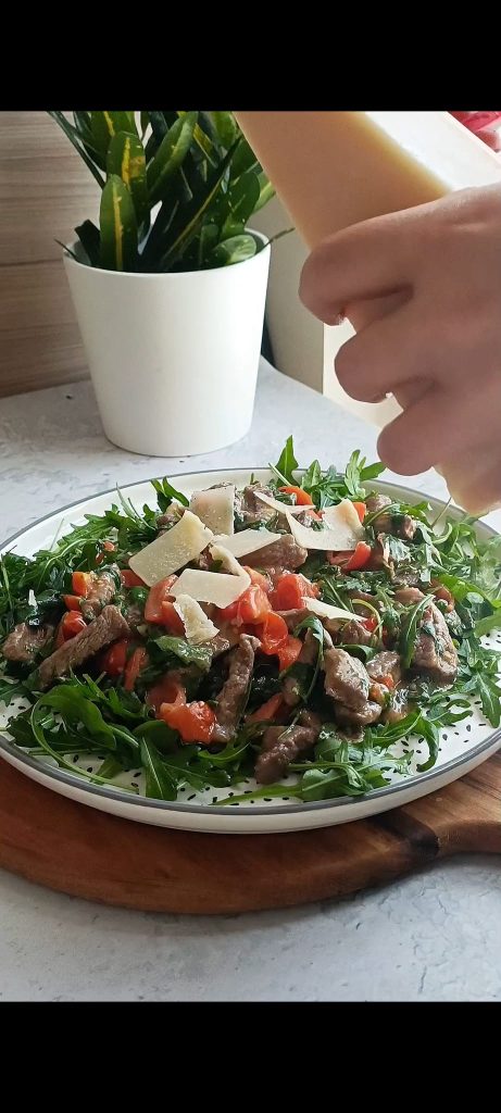 Prato com rúcula, carne, tomatinhos, lascas de grana
