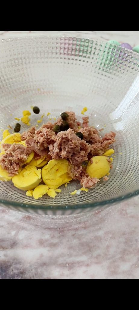 Misturando gemas, atum, alcaparras, azeitonas e queijo