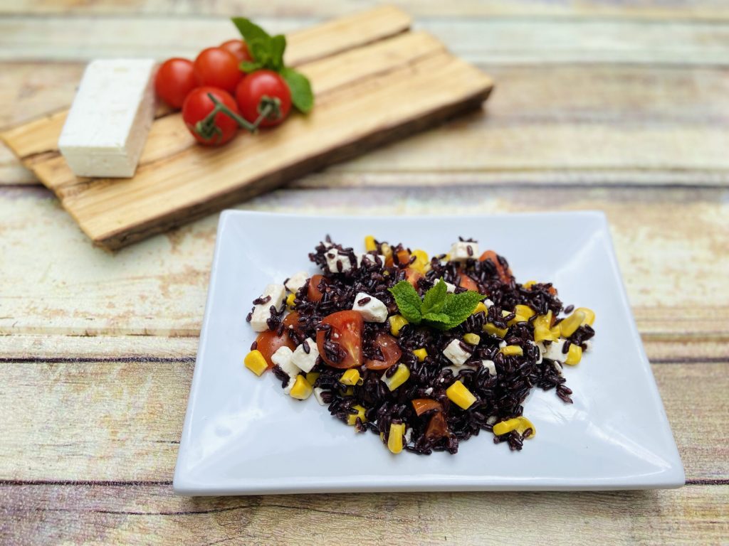 Arroz negro com feta, milho e tomatinhos