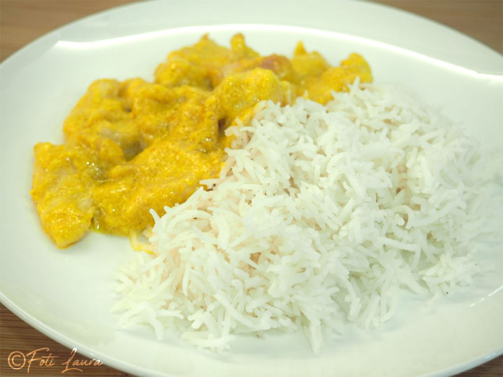 Arroz basmati servido em um prato branco junto com frango ao curry