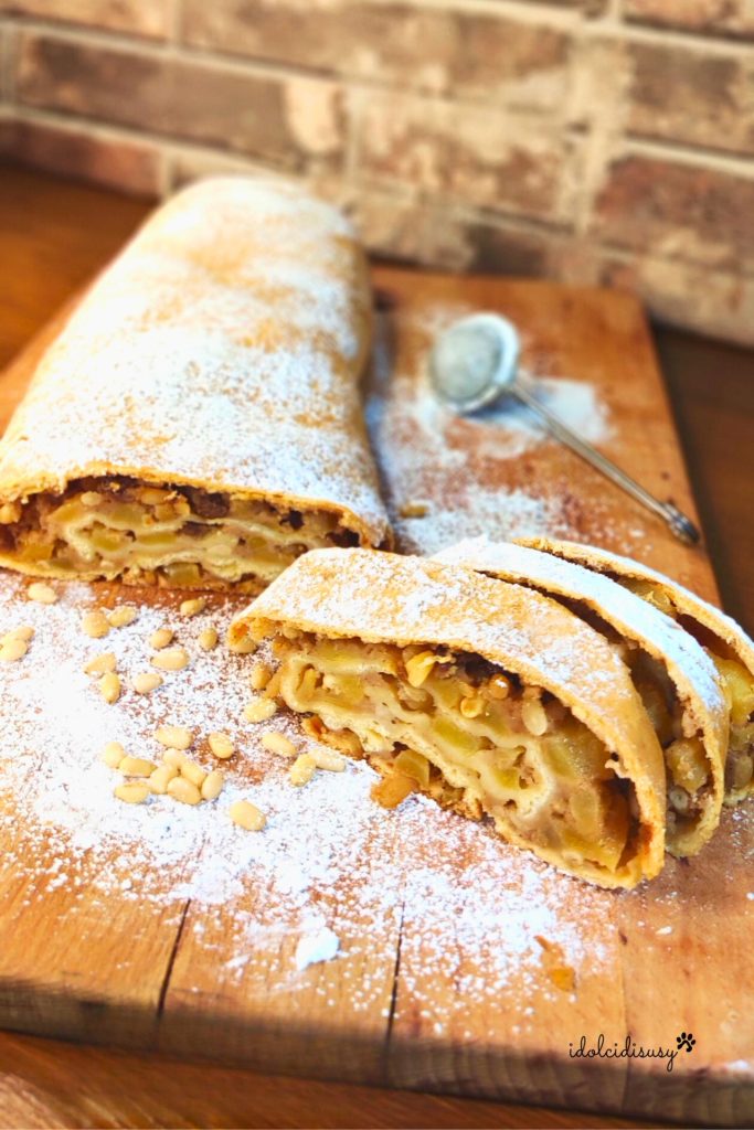 Strudel de maçã feito em casa com massa fina e recheio de maçãs, uvas-passas e pinhões, polvilhado com açúcar de confeiteiro