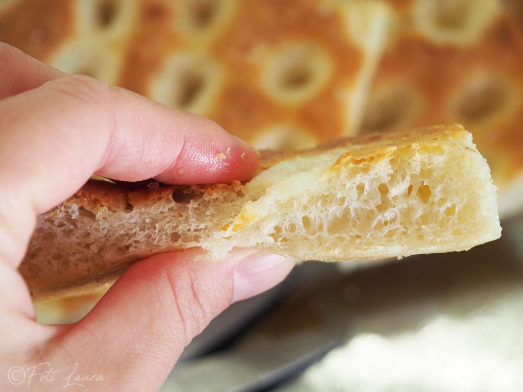 Pedaço de focaccia entre os dedos para testar a maciez e a crocância