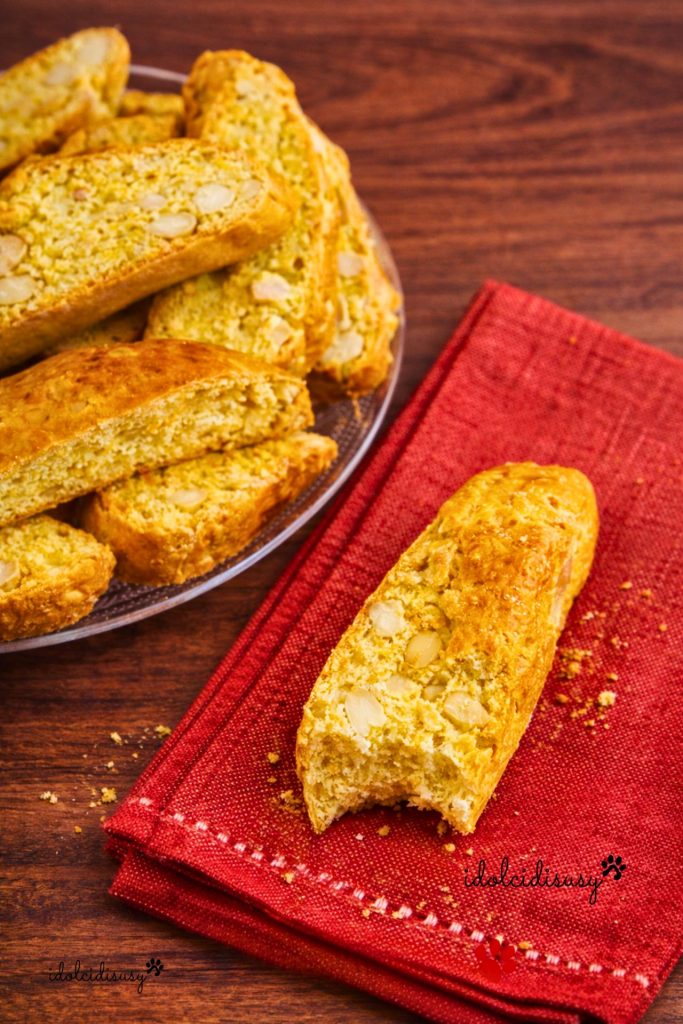 Cantucci com amêndoas feitos em casa, biscoitos toscanos crocantes com amêndoas inteiras, servidos em guardanapo vermelho com um cantucci mordido