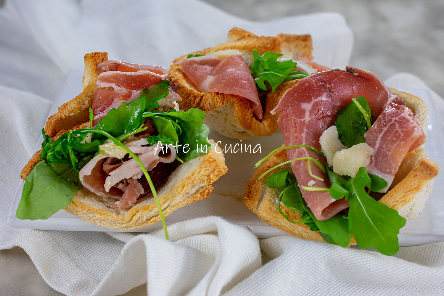 Cestinhas de pão com speck, rúcula e parmesão
