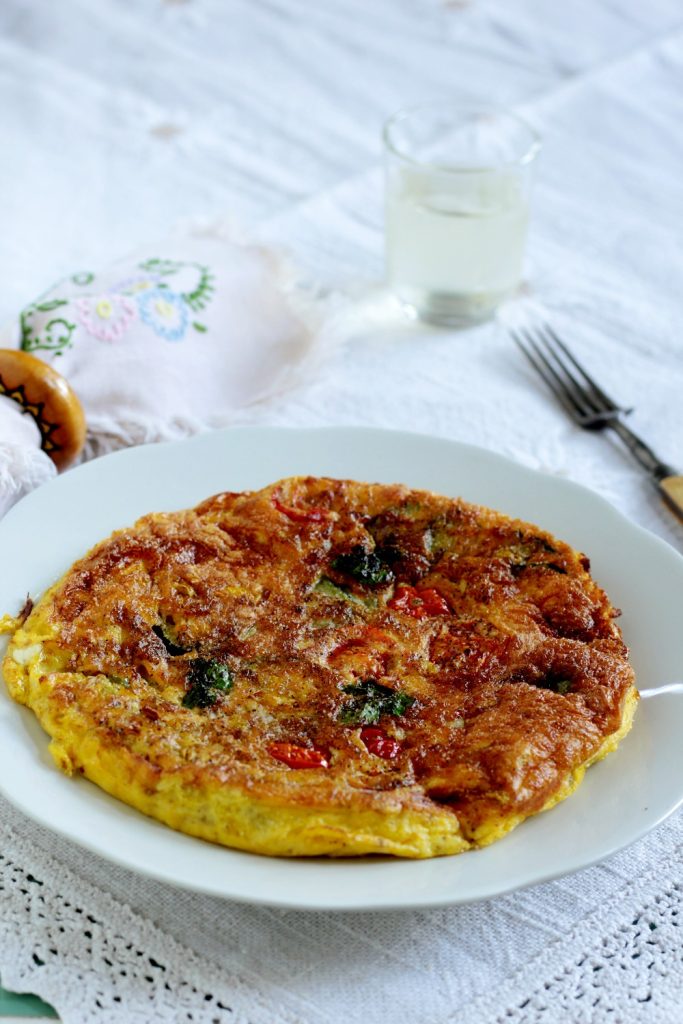 Fritada inteira de abobrinha e tomatinhos servida numa mesa posta