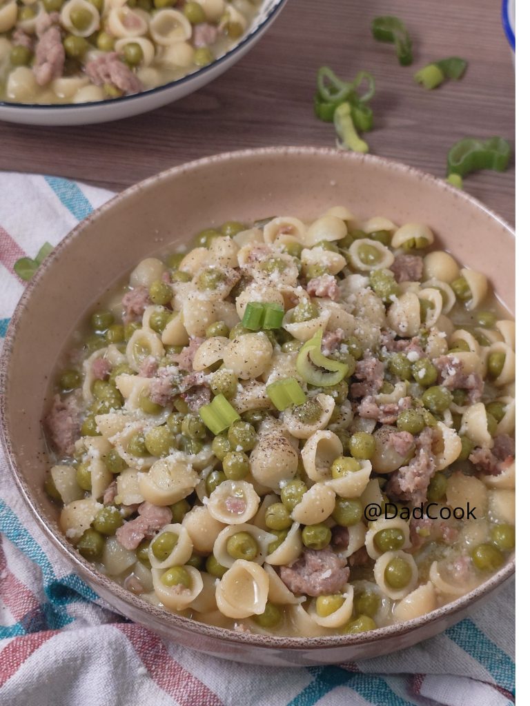 Macarrão com ervilhas cremoso e linguiça fresca em uma panela.
