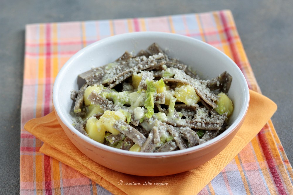 Close horizontal de pizzoccheri da Valtellina com repolho e fontina puxante recém-saídos da assadeira.