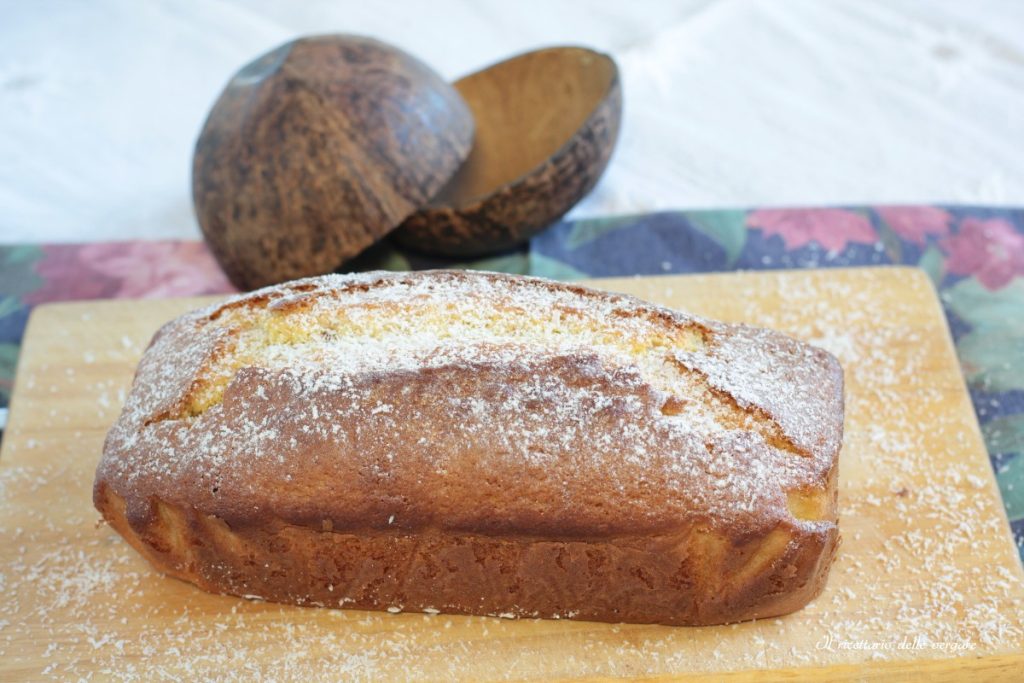Plumcake de coco macio polvilhado com coco ralado (rapê) sobre uma tábua de madeira.