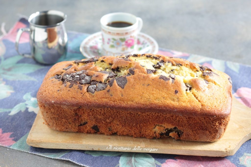 Plumcake dos 7 potes de iogurte com chocolate inteiro sobre uma tábua ao lado de uma xícara de café