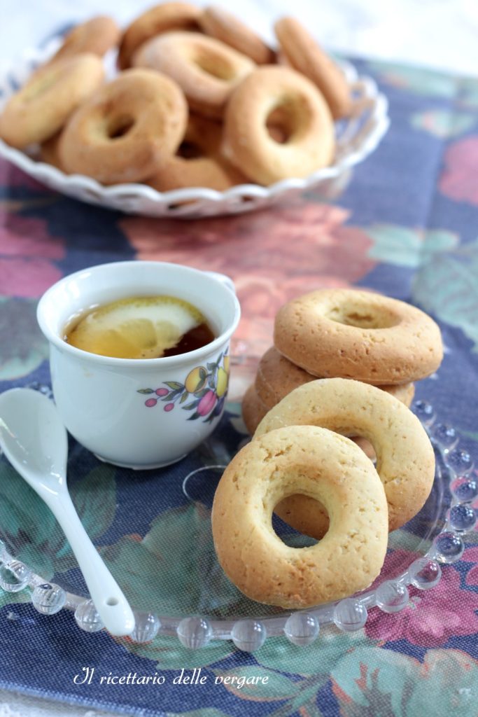 Rosquinhas macias com creme de leite sem manteiga empilhadas em um prato de vidro perto de uma xícara de chá.