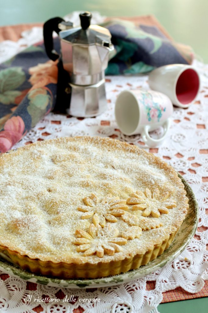 Torta coberta de cerejas e maçãs inteira, com decorações de massa em forma de flor e polvilhada com açúcar de confeiteiro.