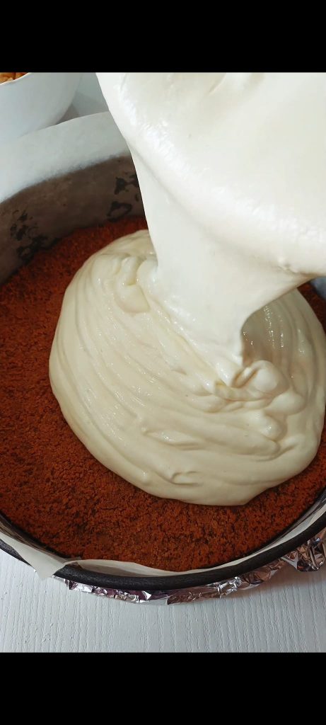 Giet de roomkaas op de koekjesbodem